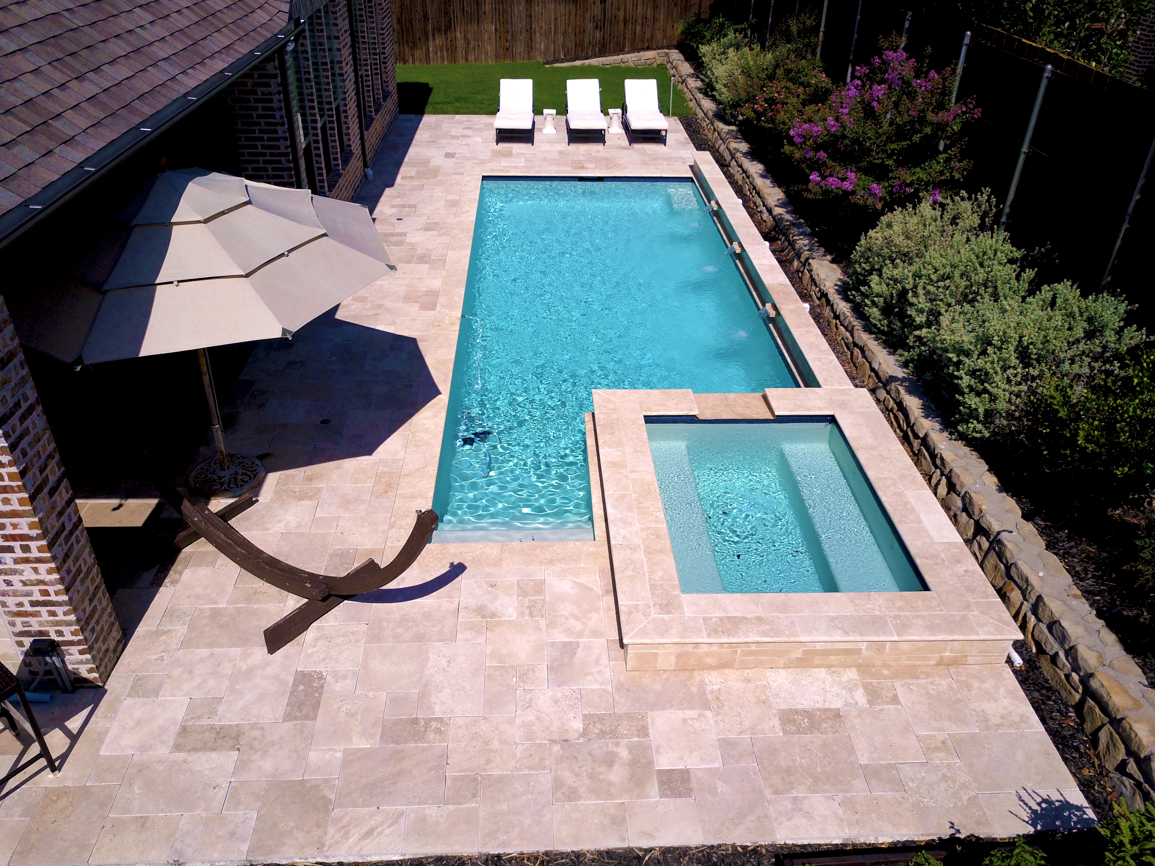 A pool with an umbrella and chairs in the middle of it.