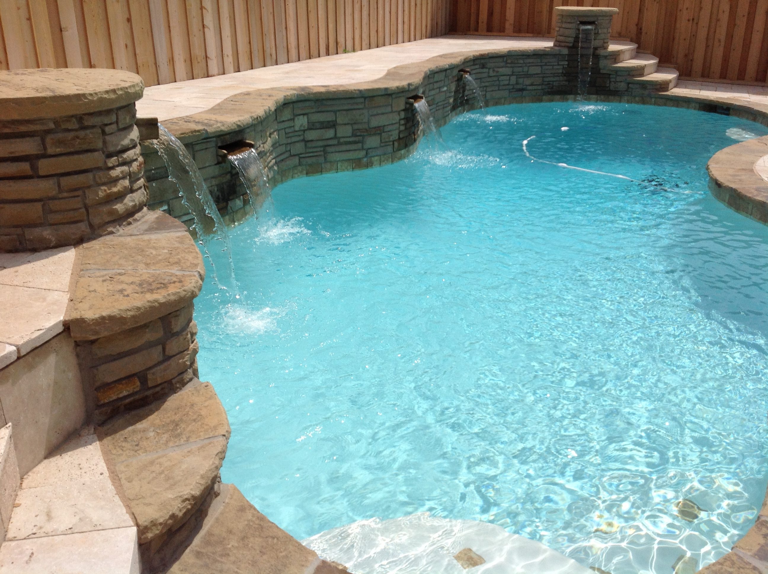 A pool with water falling into it and rocks on the side.