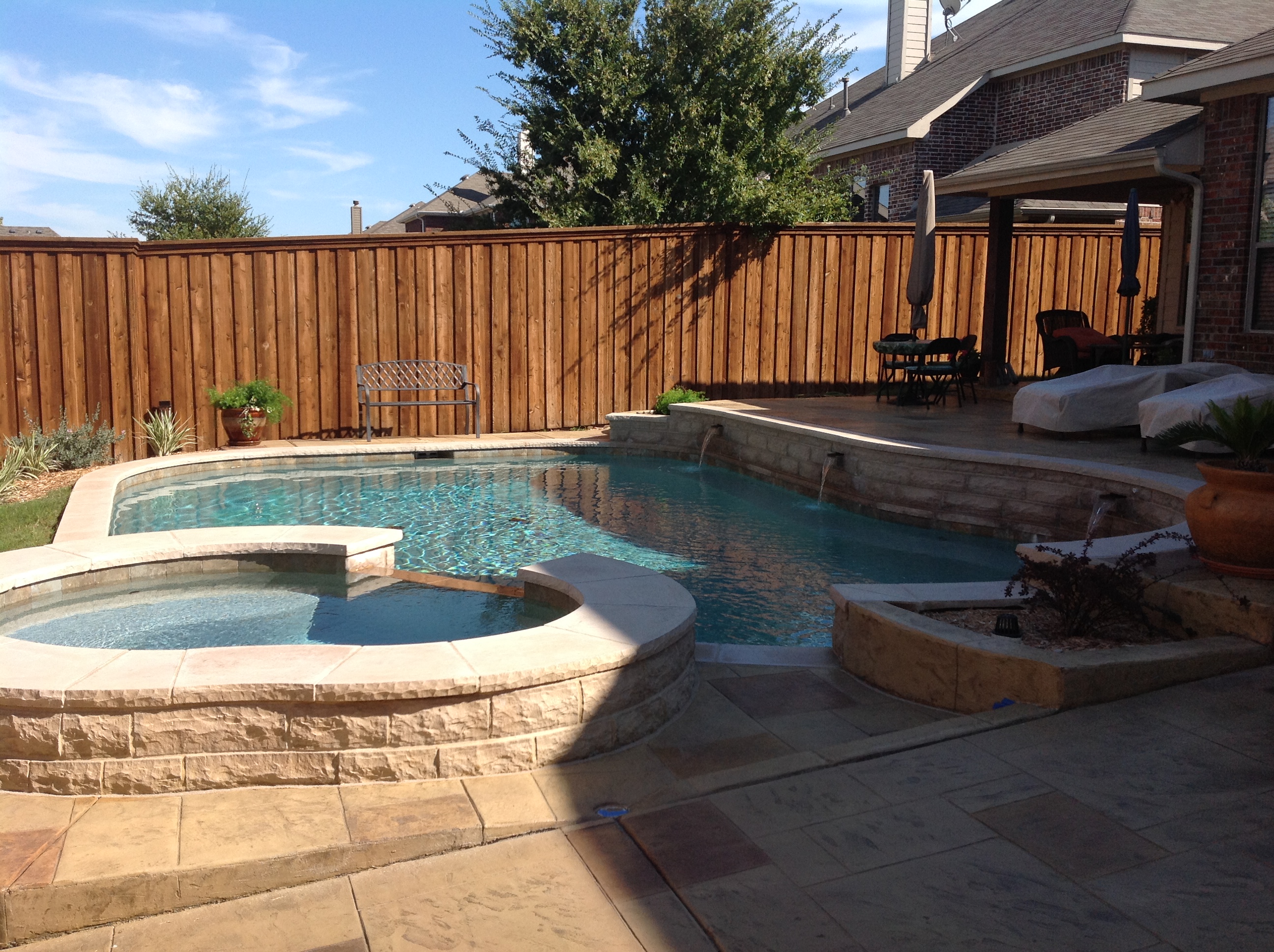 A pool with a jacuzzi and a patio.