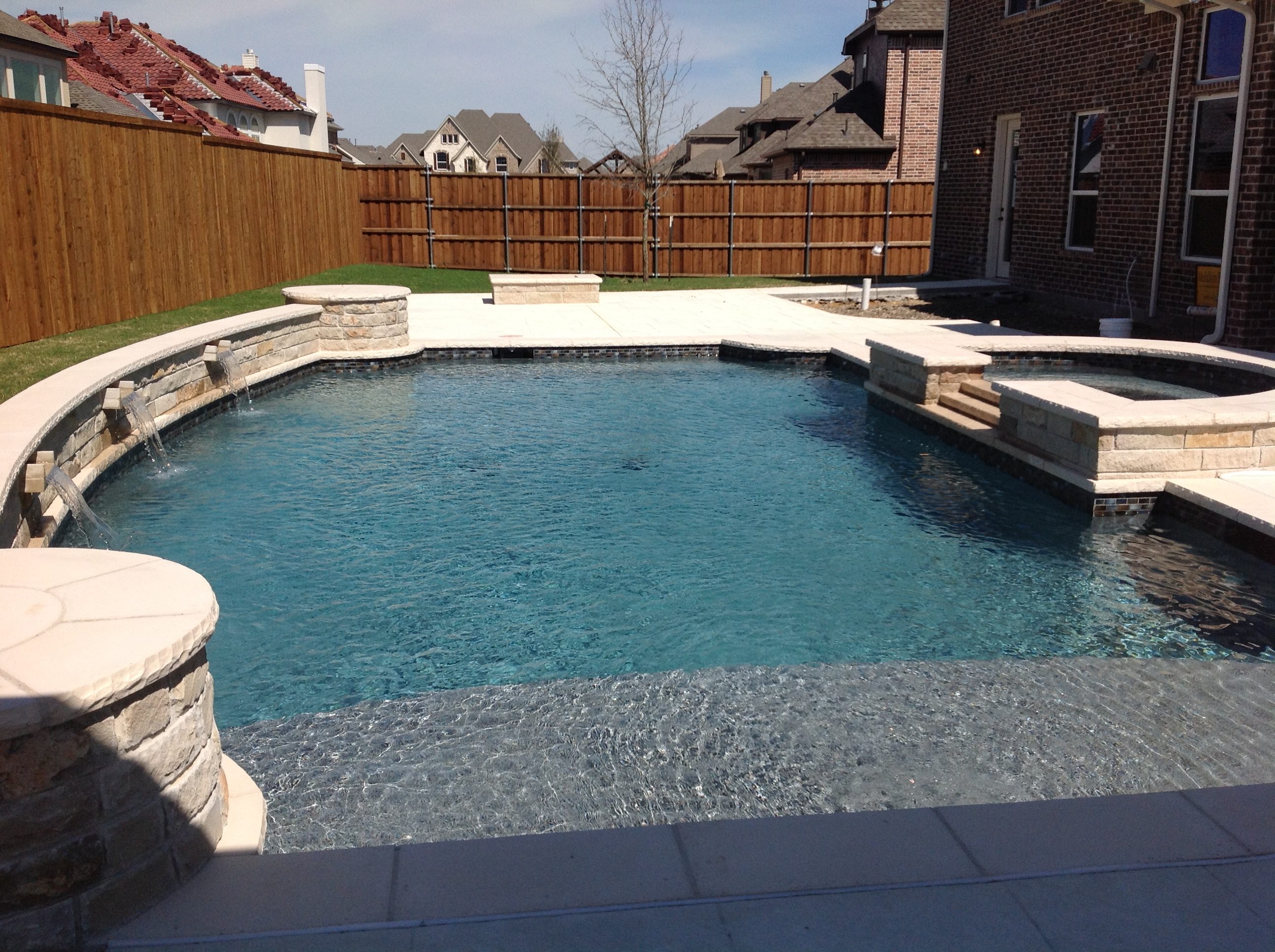 A pool with a stone wall and a large bench.